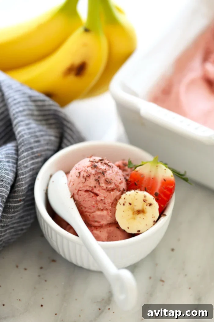 A bowl of delicious Protein Strawberry Banana Nice Cream, garnished with fresh strawberries and banana slices.