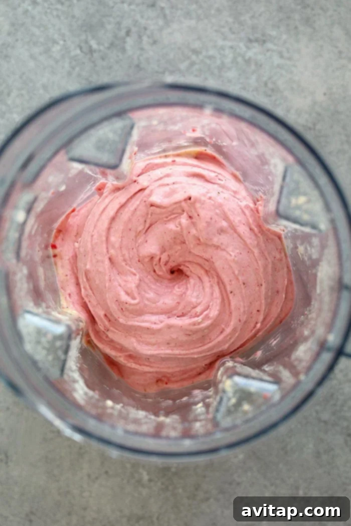 Frozen bananas and strawberries being blended into nice cream in a high-speed Vitamix blender.