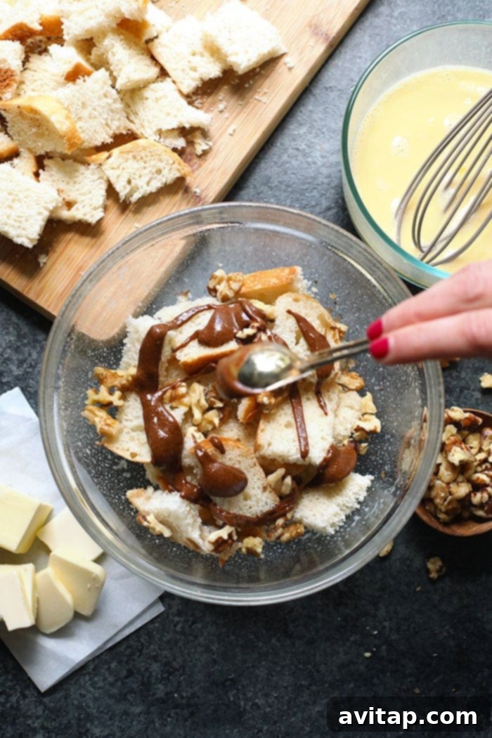 Assortment of fresh ingredients for French toast casserole, including sourdough bread cubes, eggs, milk, walnuts, and almond butter, neatly arranged in a bowl.