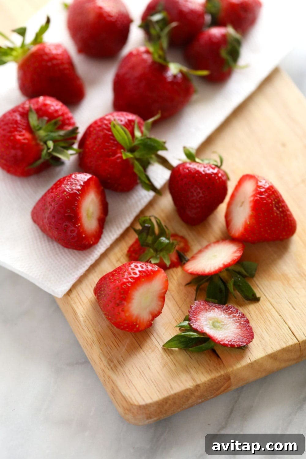 Sliced strawberries drying on a cutting board, ready for freezing.