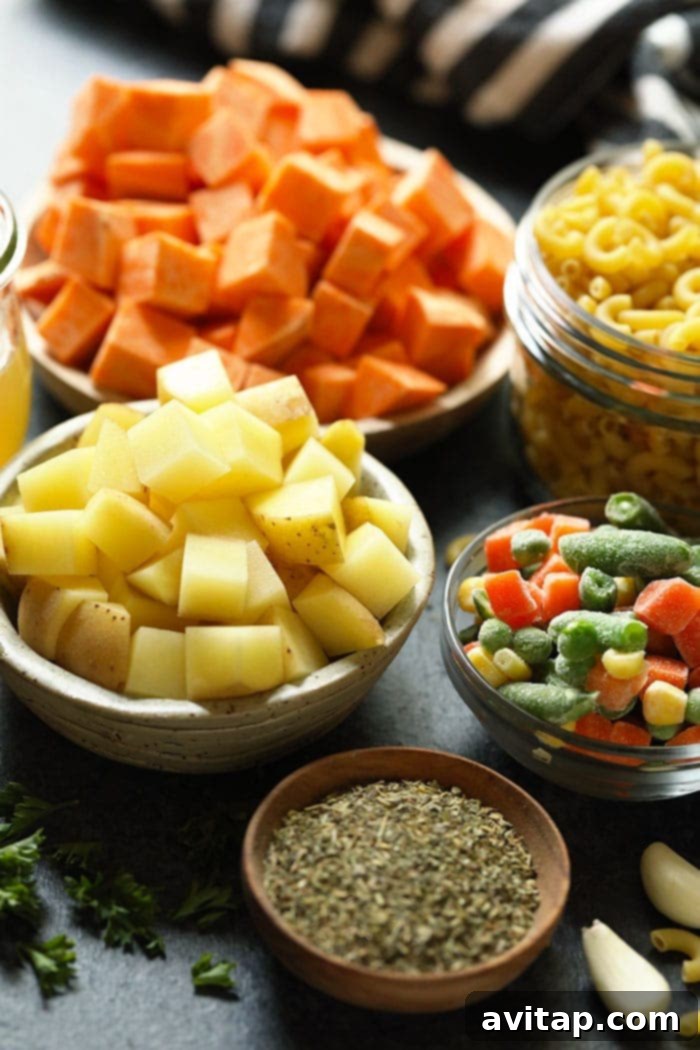 Assortment of fresh ingredients for hamburger soup displayed in small bowls, including diced vegetables, spices, and broth.