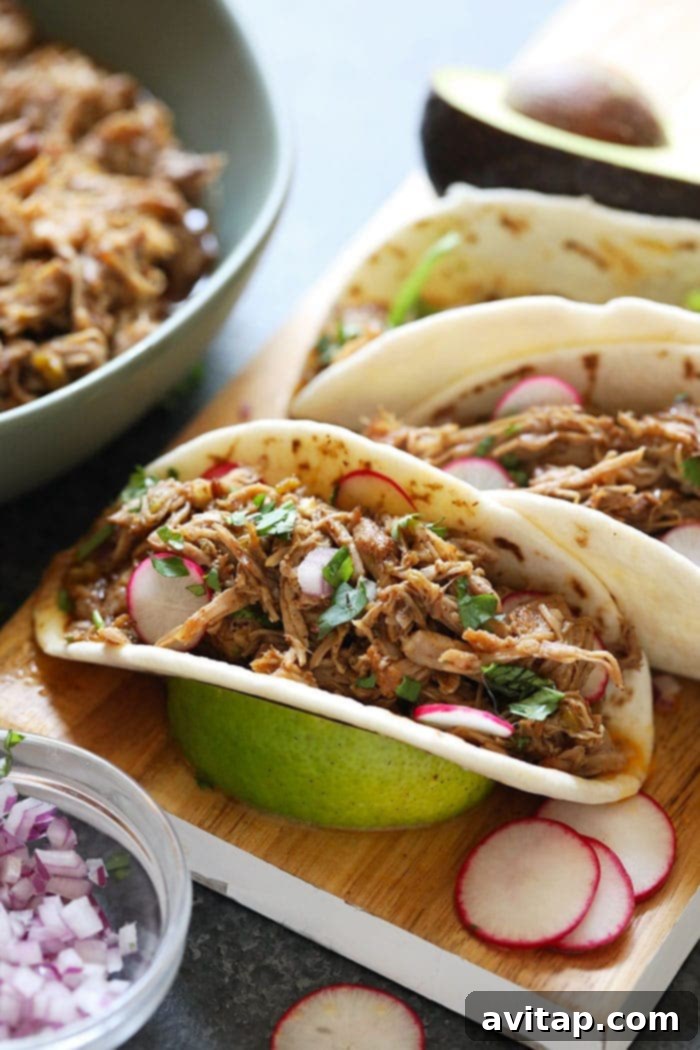 Delicious Instant Pot Carnitas tacos with fresh cilantro and lime on a cutting board