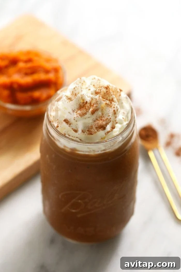 Healthy Pumpkin Coffee Smoothie Delicious pumpkin smoothie in a glass jar with a straw, topped with whipped cream and a sprinkle of pumpkin pie spice.