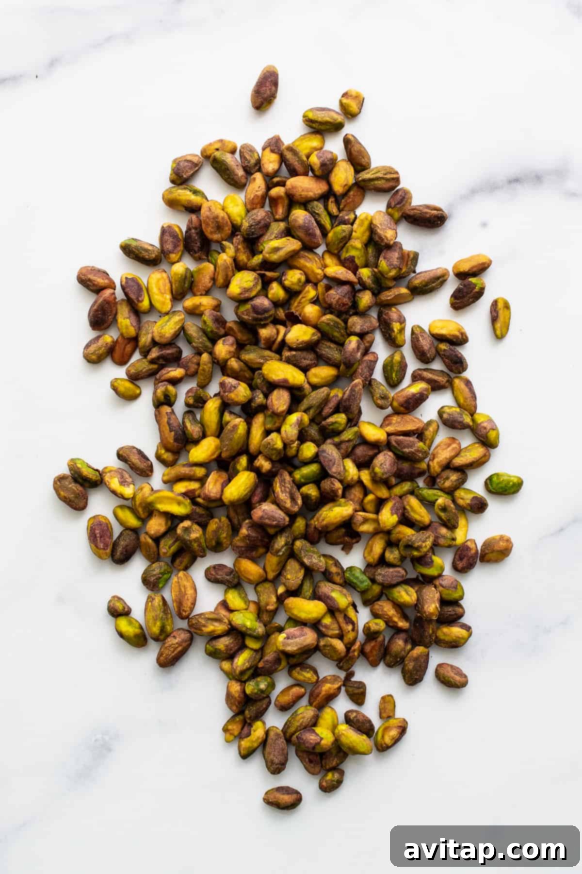 Shelled, raw pistachios neatly arranged on a kitchen counter.