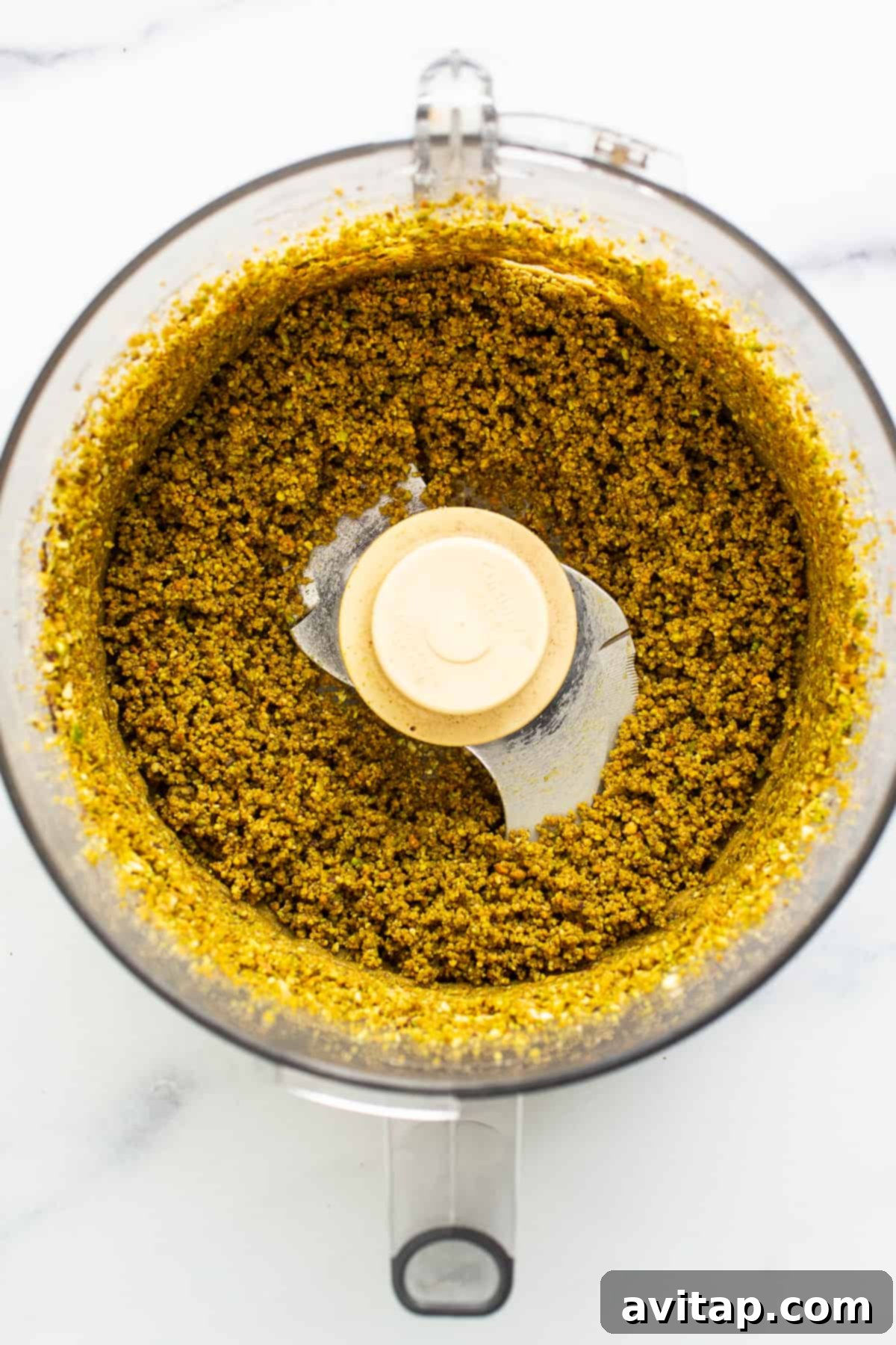 Pistachios being processed into butter in a food processor.