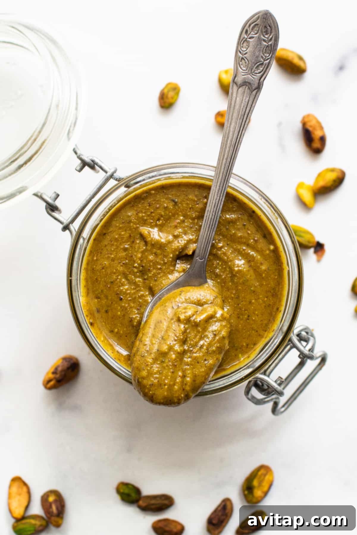 Smooth homemade pistachio butter in a clear glass container.