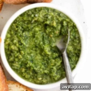 A bowl of homemade pesto, elegantly presented with fresh basil and slices of bread, inviting a taste.