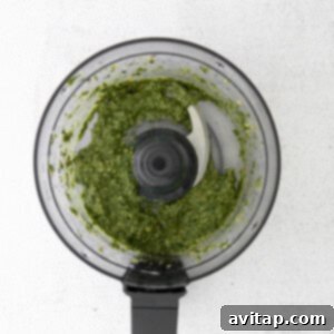 Pesto actively being processed in a food processor, transforming into a smooth, vibrant green sauce.
