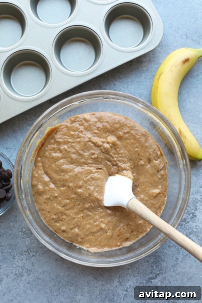 Close-up shot of rich banana chocolate chip muffin batter in a mixing bowl, showcasing its smooth texture.