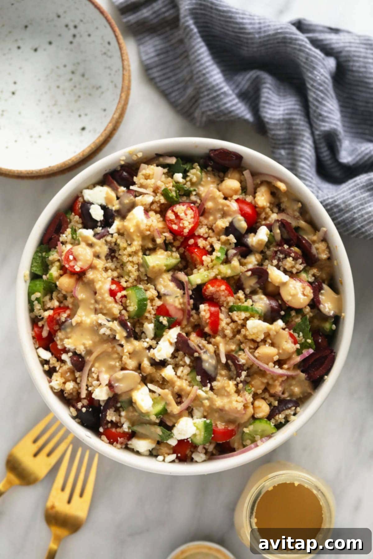 Vibrant Mediterranean Quinoa Salad in a bowl, drizzled with creamy hummus dressing, ready to be enjoyed.