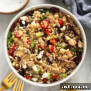 A beautifully presented quinoa salad in a white bowl with a fork, ready to be enjoyed.
