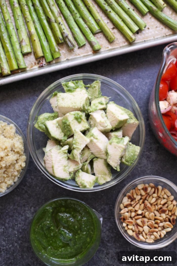 Pesto chicken ready in a bowl, waiting to be combined with roasted asparagus and other fresh ingredients.