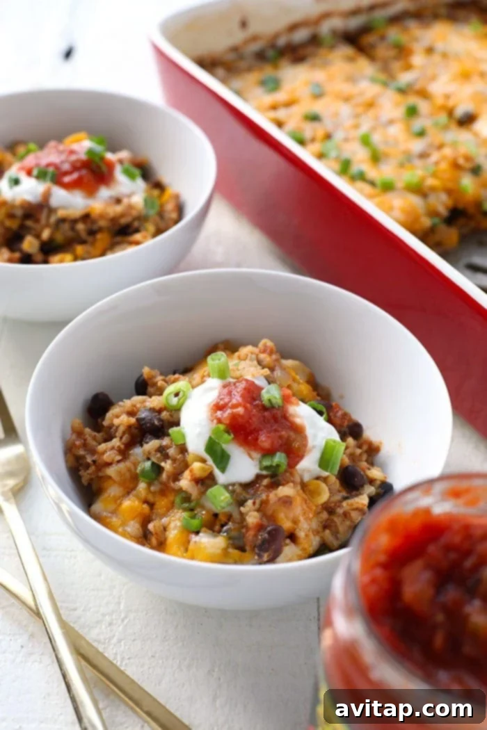 A serving of Southwestern Chicken Casserole topped with a dollop of Greek yogurt, fresh salsa, and vibrant green onions.