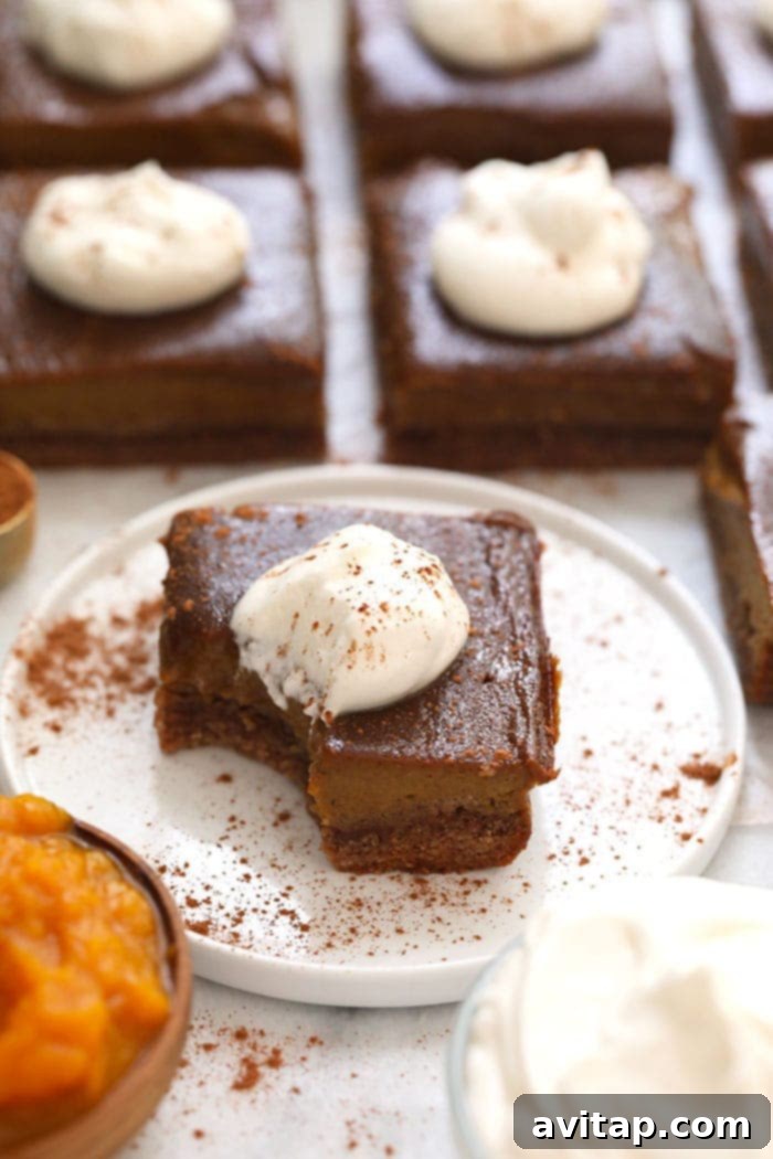 A perfectly portioned healthy pumpkin pie bar on a clean white plate, garnished with a sprinkle of cinnamon, ready to be enjoyed as a fall or Thanksgiving dessert.