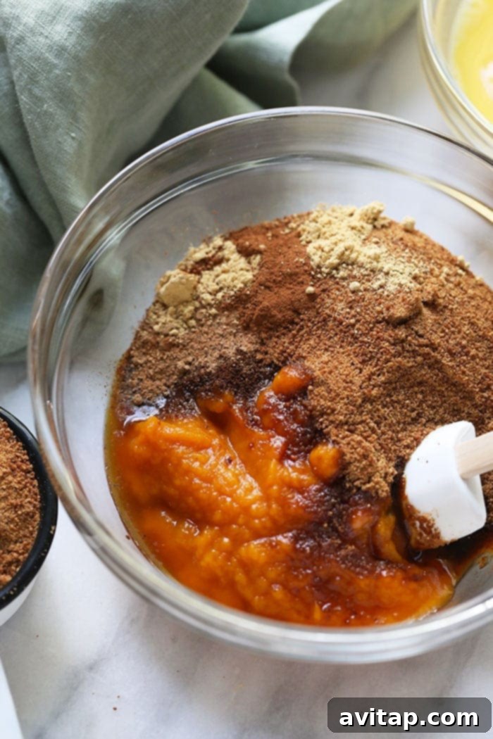 A vibrant bowl showcasing the wholesome ingredients for the pumpkin pie bar filling, including rich pumpkin puree, fresh eggs, and a selection of fragrant spices, ready for mixing.