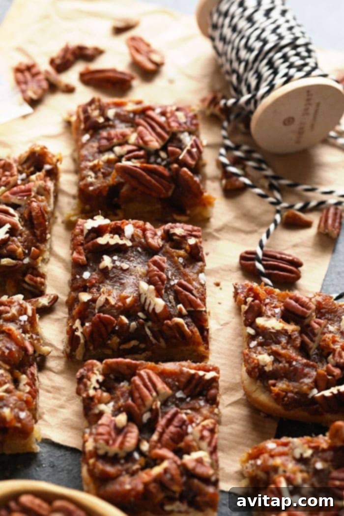 Healthy Pecan Pie Bars with Date Caramel and Almond Shortbread Crust Delicious finished pecan pie bars stacked on a plate, ready to be enjoyed.