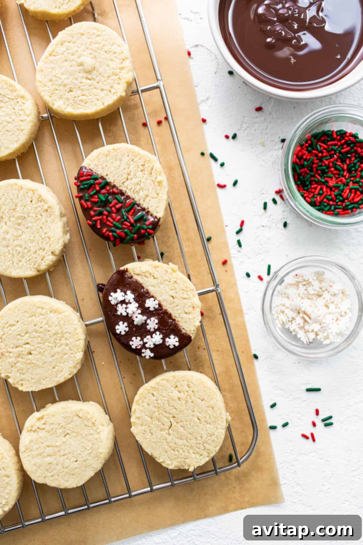 Beautifully decorated almond flour shortbread cookies cooling on a wire rack, adorned with melted chocolate and festive sprinkles.
