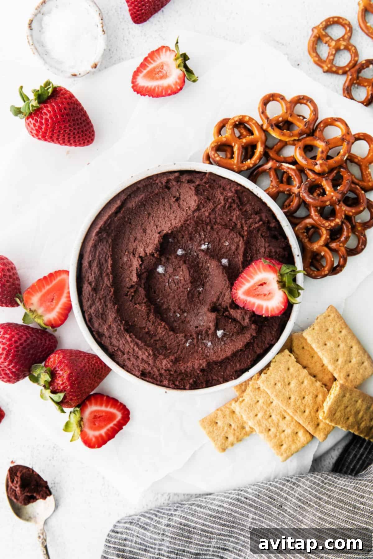 A serving bowl filled with creamy, dark chocolate hummus, garnished beautifully and ready for serving.