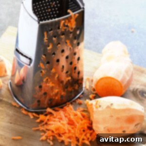 A cutting board with sweet potato hash browns being grated.