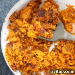 Sweet potato hash browns in a pan with a spatula, mid-flip.