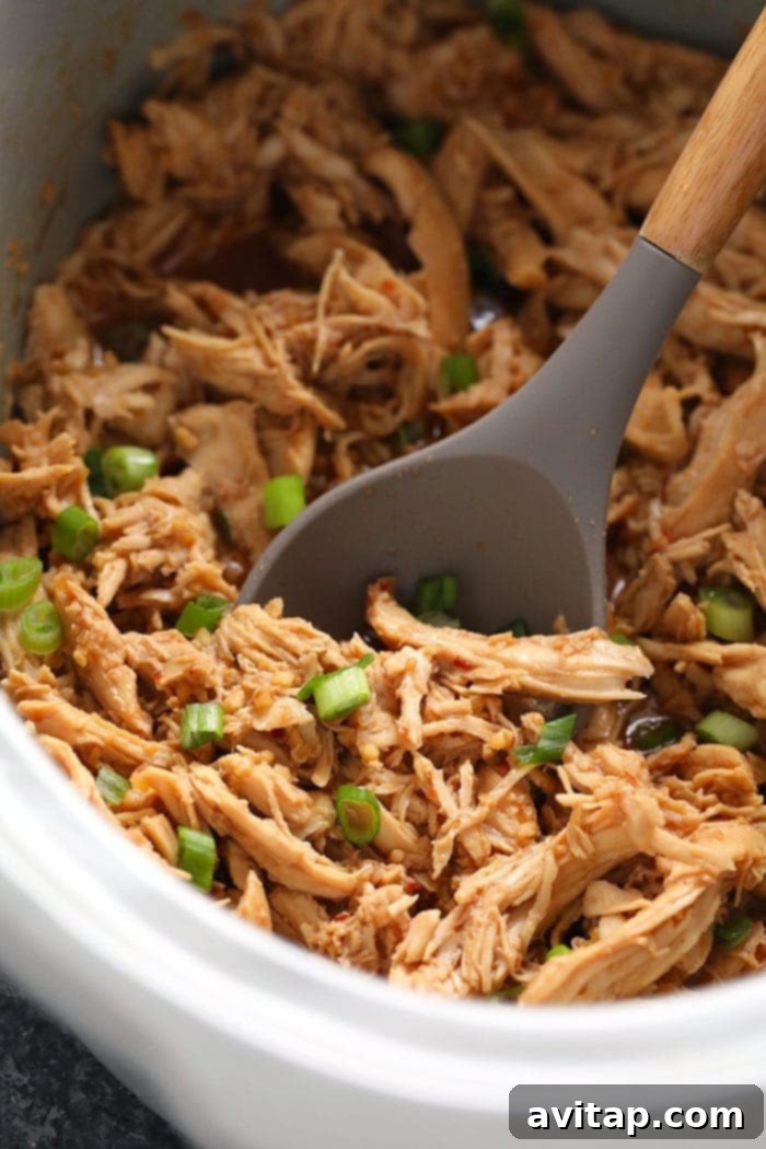 Sticky Honey Garlic Chicken 5 Shredded honey garlic chicken simmering in the slow cooker, ready to be served.