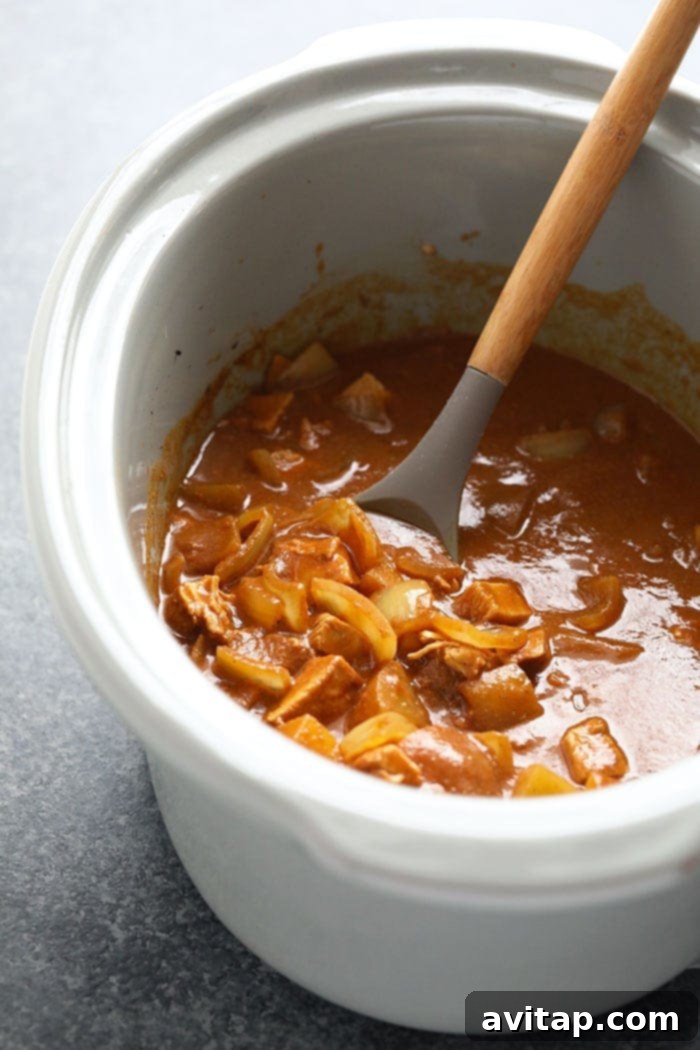 Slow Cooker Chicken Tikka Masala Cooking Close-up of slow cooker chicken tikka masala simmering in a crock pot, showing ingredients mixing.