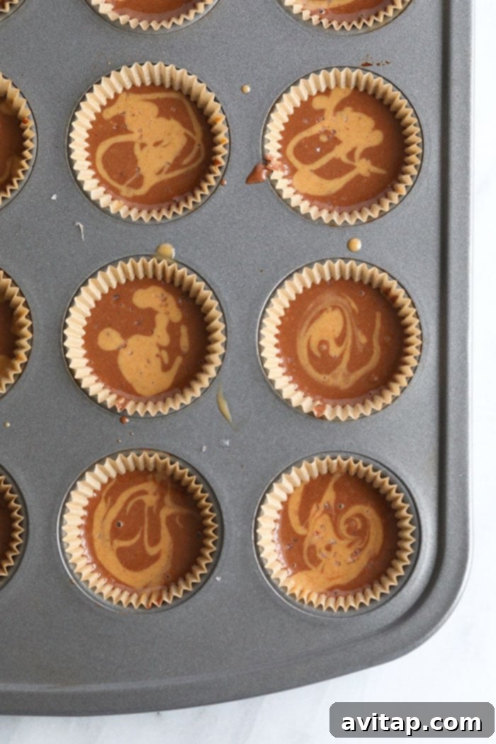 Chocolate Peanut Butter Fat Bomb batter poured into mini muffin tins, ready for freezing.