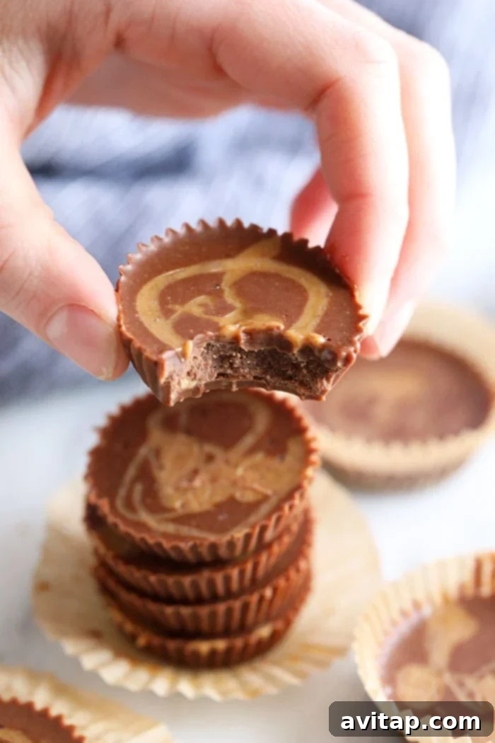 A hand holding a perfectly formed Chocolate Peanut Butter Fat Bomb, showcasing its smooth texture.