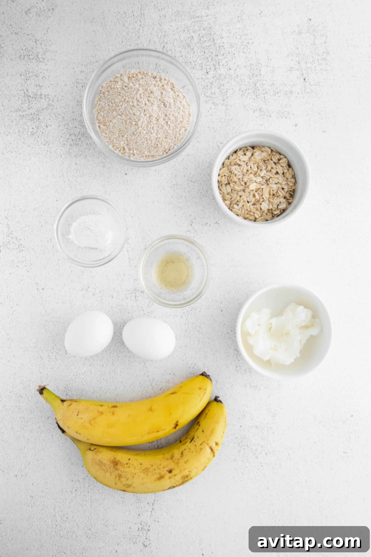 Essential Ingredients for Healthy Banana Oatmeal Pancakes A collection of fresh ingredients for banana oatmeal pancakes laid out on a kitchen counter, including ripe bananas, oats, eggs, and coconut oil.