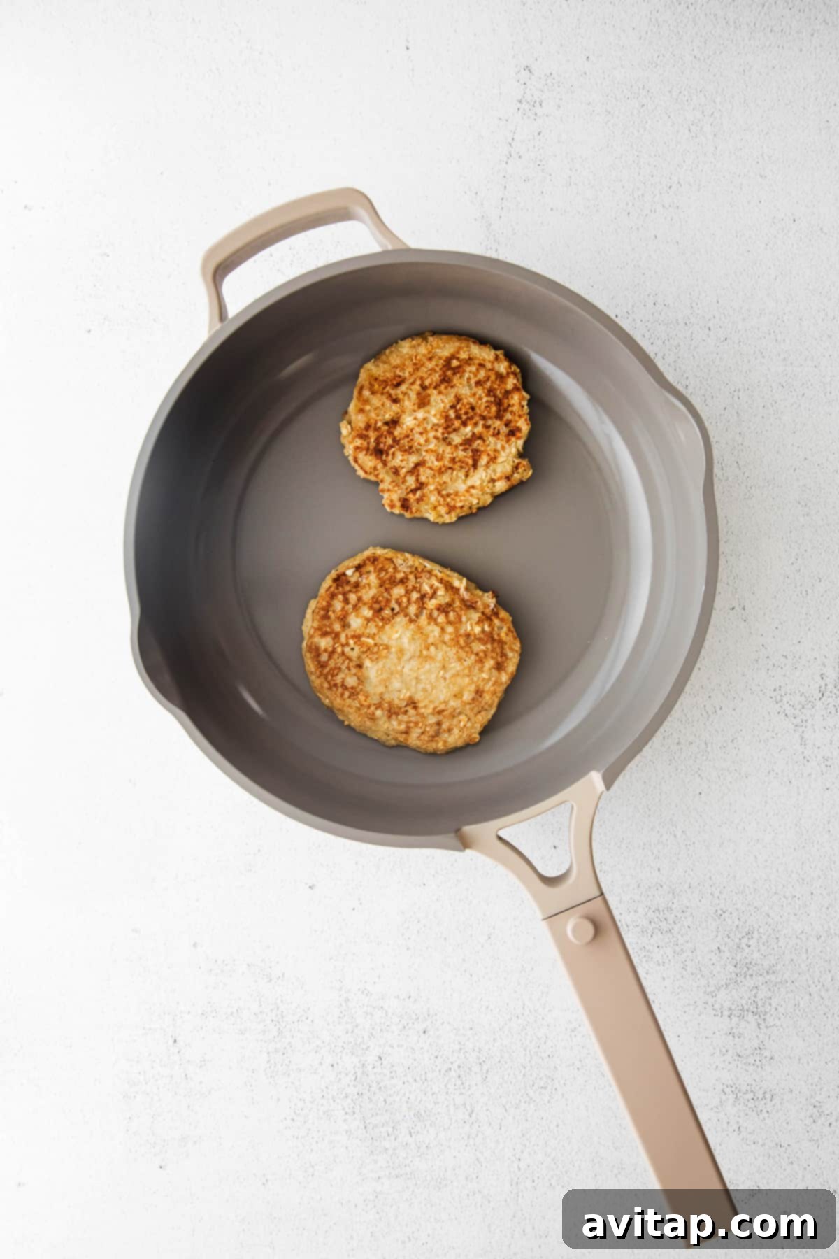 Cooking Golden Banana Oatmeal Pancakes on a Skillet Several banana oatmeal pancakes cooking on a skillet, turning golden brown.