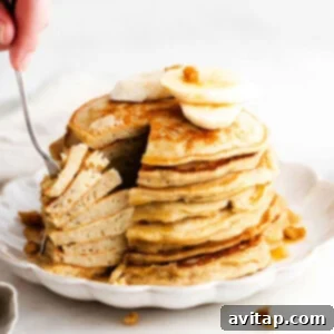 Fluffy Banana Oat Pancakes 2 A stack of fluffy banana pancakes, topped with fresh banana slices and maple syrup.
