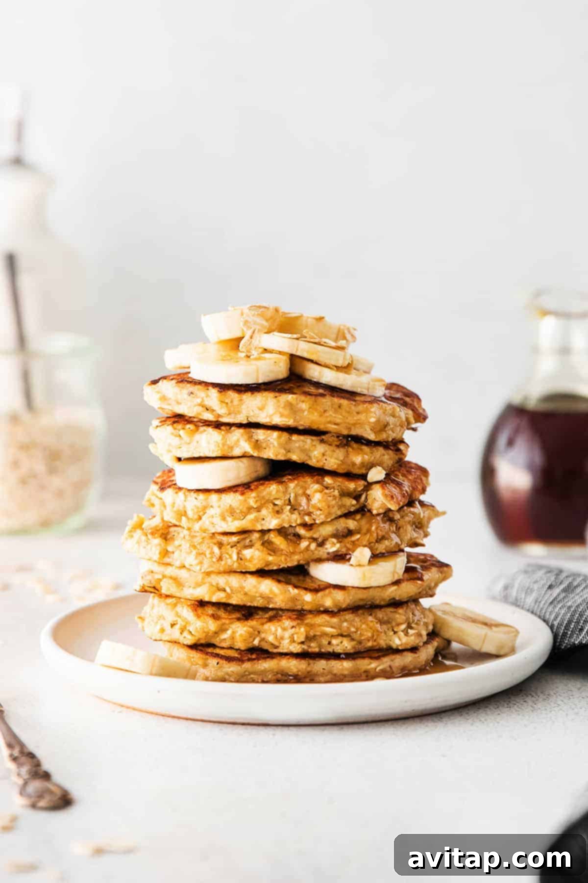 Delicious Banana Oatmeal Pancakes with Fresh Toppings A beautifully styled stack of banana oatmeal pancakes, adorned with sliced bananas, rolled oats, and a drizzle of syrup.