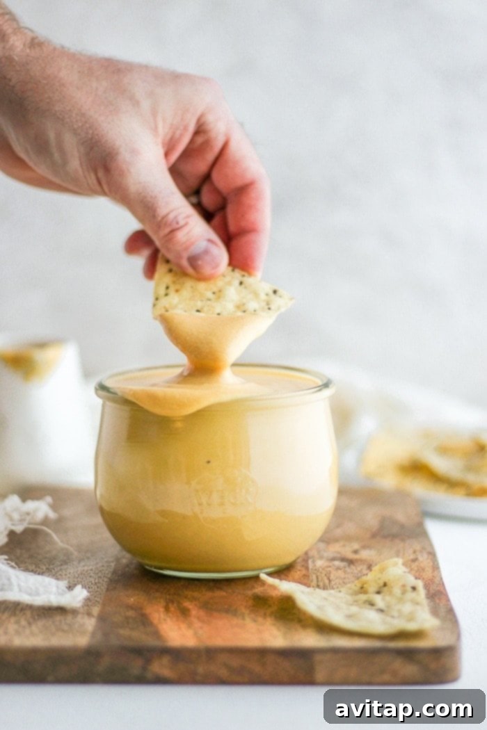 Vegan Cheese Sauce being poured onto food, highlighting its creamy texture.
