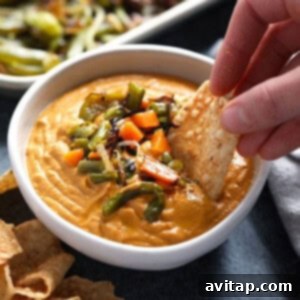 A bowl of rich vegan queso with tortilla chips.