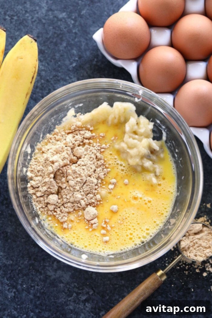 Simple Ingredients for Protein-Packed Pancakes A bowl filled with the simple three ingredients: mashed banana, eggs, and peanut flour, ready to be mixed for healthy pancakes.
