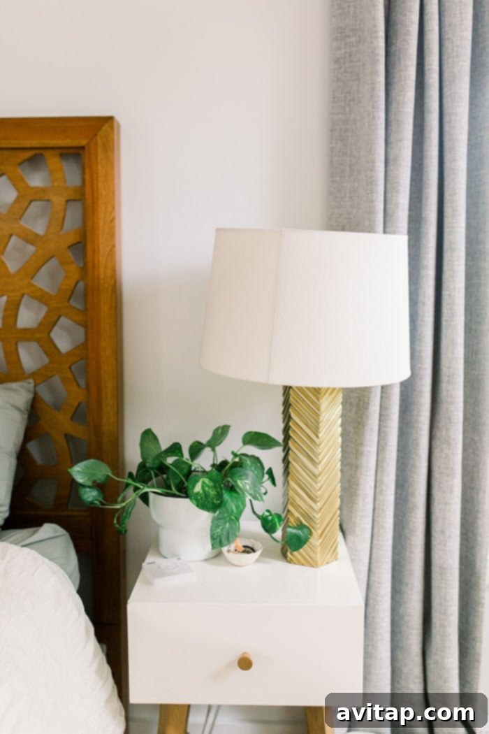 Stylish table lamp on a nightstand with a plant, adding a warm glow to the bedroom decor.
