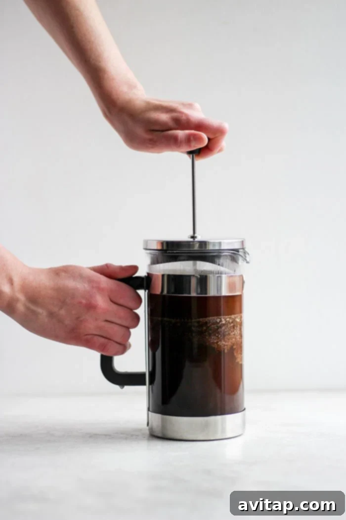 A pot of French press coffee brewing, showcasing the rich color.
