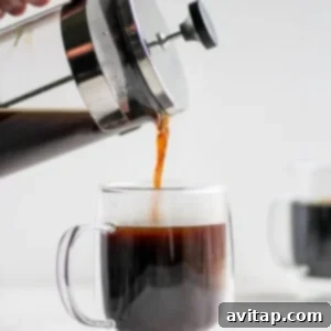 A person pouring French press coffee into a glass mug.