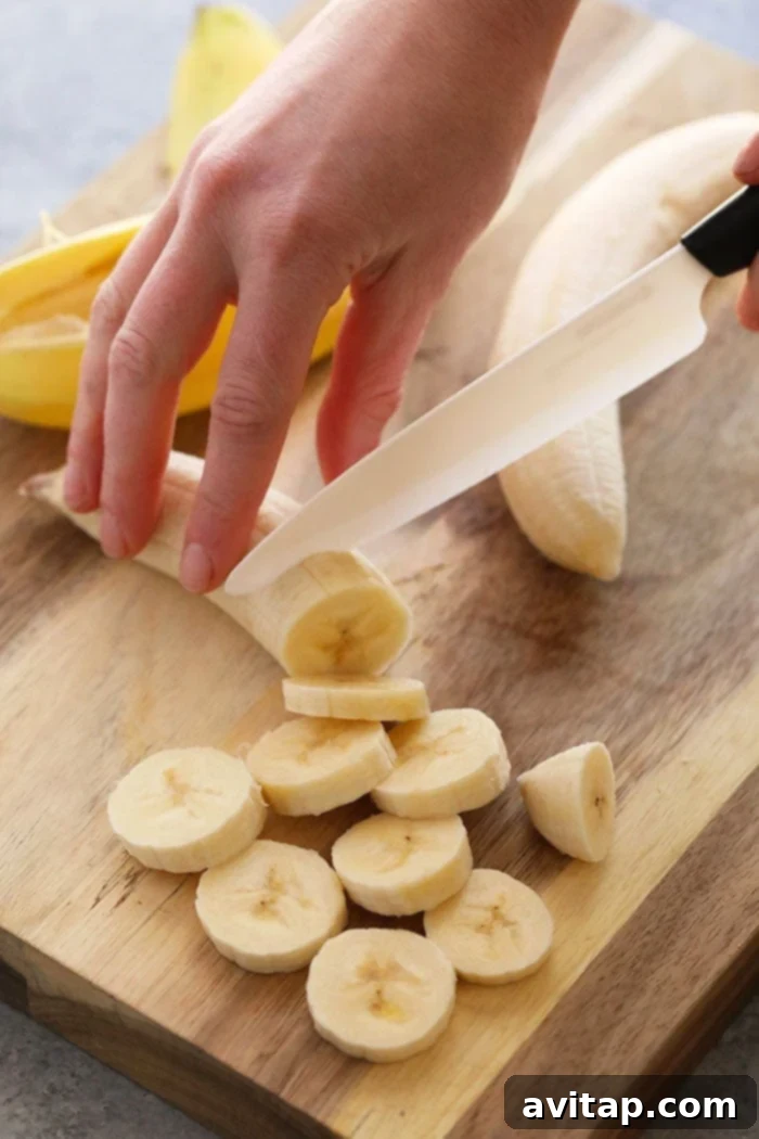 Expertly slicing ripe bananas into uniform rounds on a clean cutting board in preparation for freezing