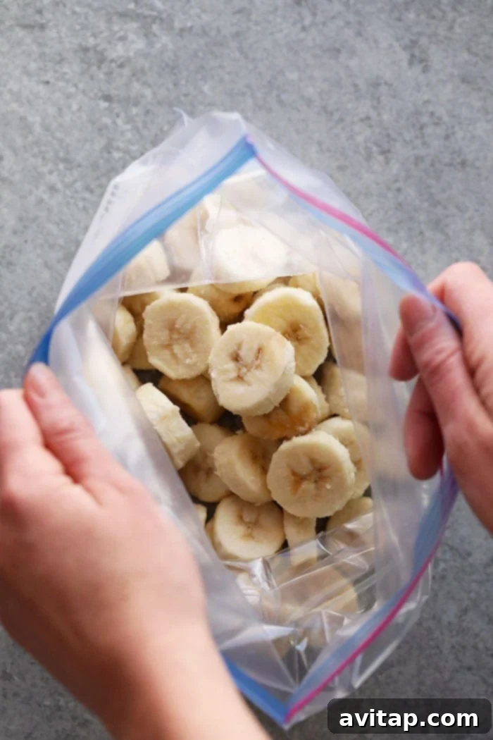 A transparent freezer-safe bag abundantly filled with individual, perfectly frozen banana slices, clearly labeled with the date for organized and efficient storage