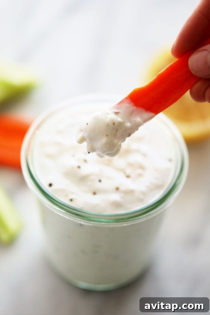 Crisp carrot sticks perfectly dipped in creamy homemade blue cheese dressing, highlighting its ideal consistency for dipping.