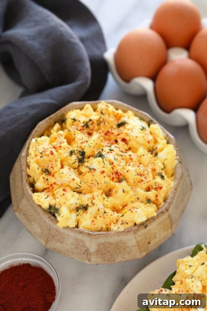 This healthy egg salad is easy to whip up for lunches on-the-go, or meal-prepped to enjoy all week long. A vibrant bowl of healthy egg salad, generously topped with fresh dill, ready to be enjoyed. This high-protein, low-carb recipe is perfect for meal prepping or on-the-go lunches.