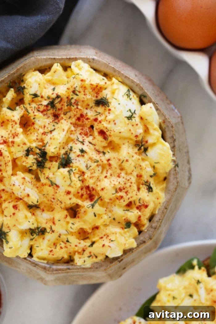 This healthy egg salad comes together with just 6 ingredients. It's a high-protein, low-carb salad that's enjoyable any day of the week. A large bowl filled with healthy egg salad, garnished with fresh herbs, ready for serving or meal prep. This image emphasizes the freshness and generous portion of the high-protein, low-carb recipe.