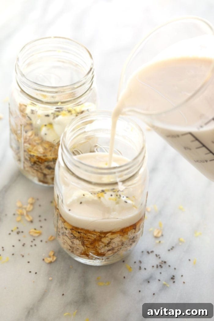 Four glass jars of Lemon Cheesecake Overnight Oats, neatly lined up and ready for refrigeration, showcasing perfect meal prep.