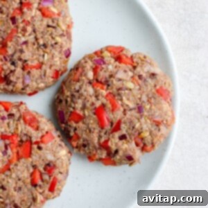 Savory Black Bean Burgers 6 Three black bean burgers topped with red peppers and onions on a plate.