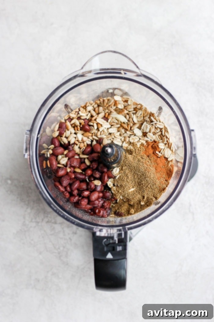 Black Bean Burger Ingredients in Food Processor A food processor filled with black beans, sunflower seeds, oats, and spices, ready to be blended into the burger mixture.