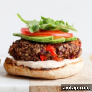 Savory Black Bean Burgers 3 A black bean burger with lettuce, tomatoes, and avocado on a cutting board, ready to be served.