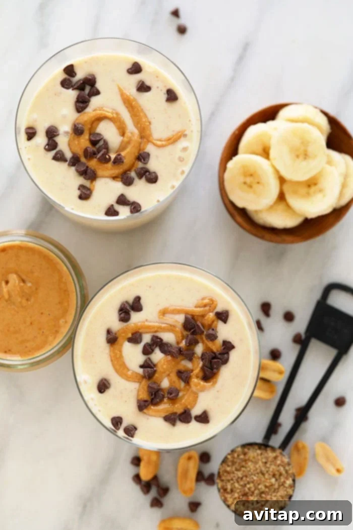Delicious PB Banana Smoothie A beautifully presented peanut butter banana smoothie in a glass, with a spoon and toppings.