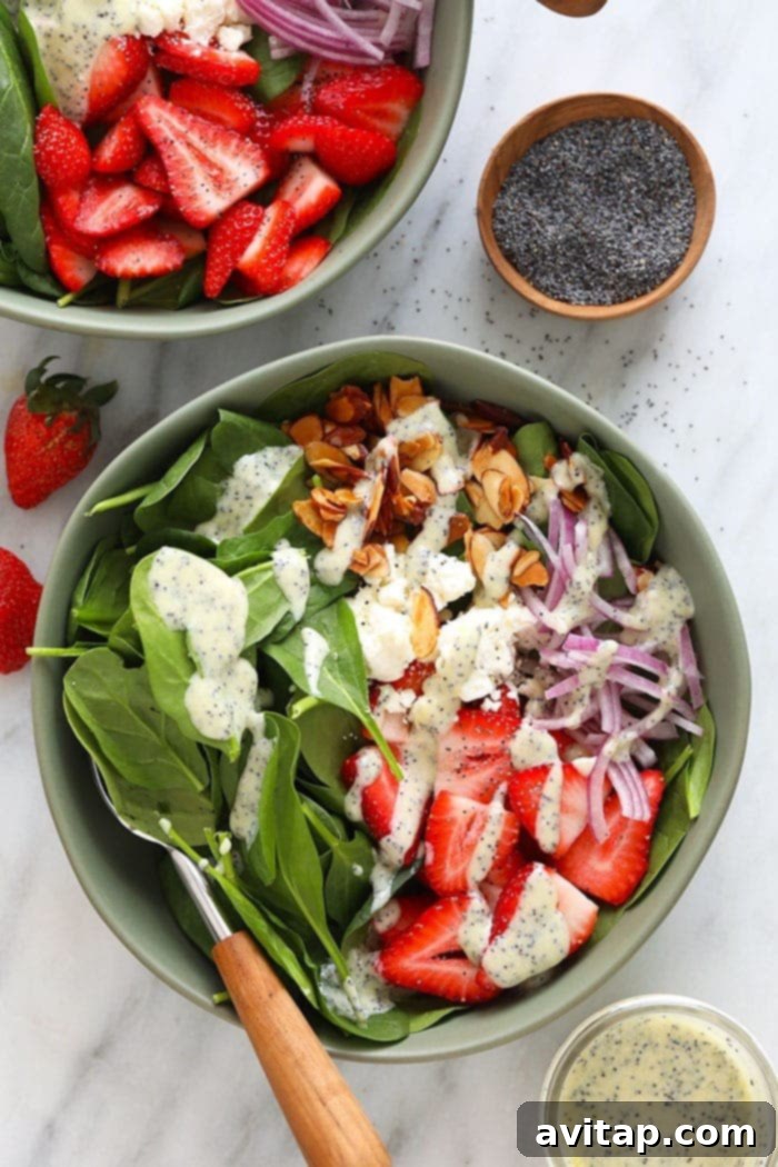 A beautifully presented Strawberry Spinach Salad with homemade poppy seed dressing in a large white bowl, garnished with fresh herbs, ready to be enjoyed.