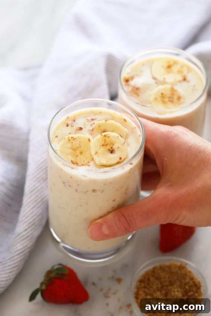 Discover the creamiest, most delicious, and healthy banana smoothie recipe. Simple to make and packed with protein, fiber, and potassium for a fantastic breakfast. A hand holding a perfectly blended, creamy banana smoothie in a glass